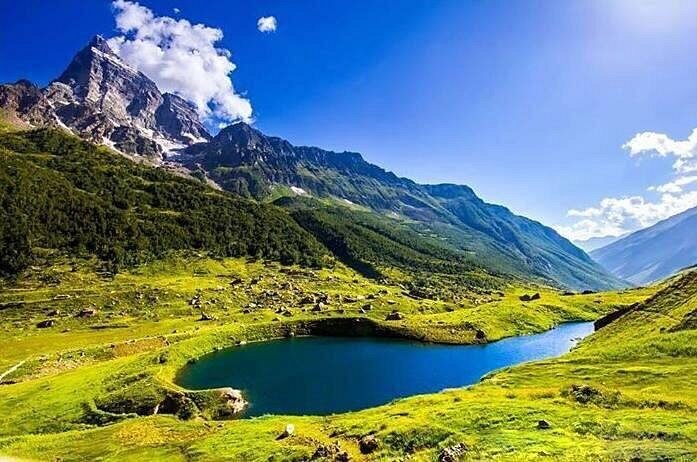 Scenic landscape of Dawar village in Gurez Valley, Jammu and Kashmir, featuring rolling meadows, sparse pine trees, rugged mountains, and a clear blue sky