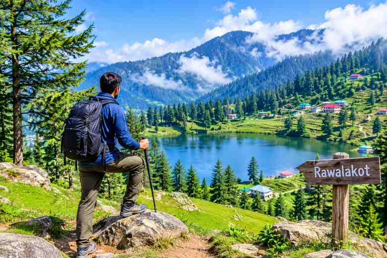 Hiker enjoying scenic lake views and green mountain trails in Rawalakot, Azad Kashmir.